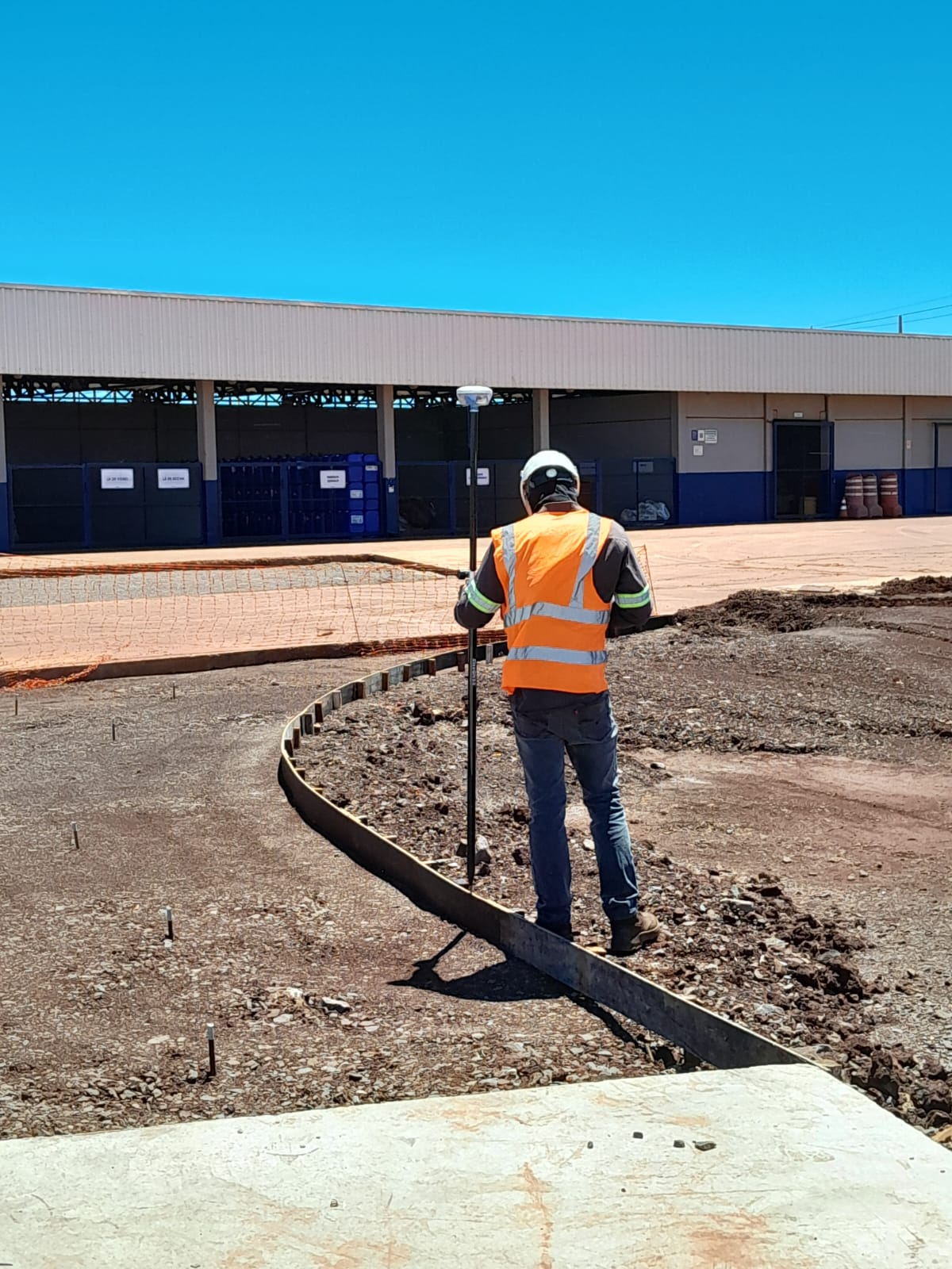 Profissional realizando levantamento topográfico em área de obra industrial.